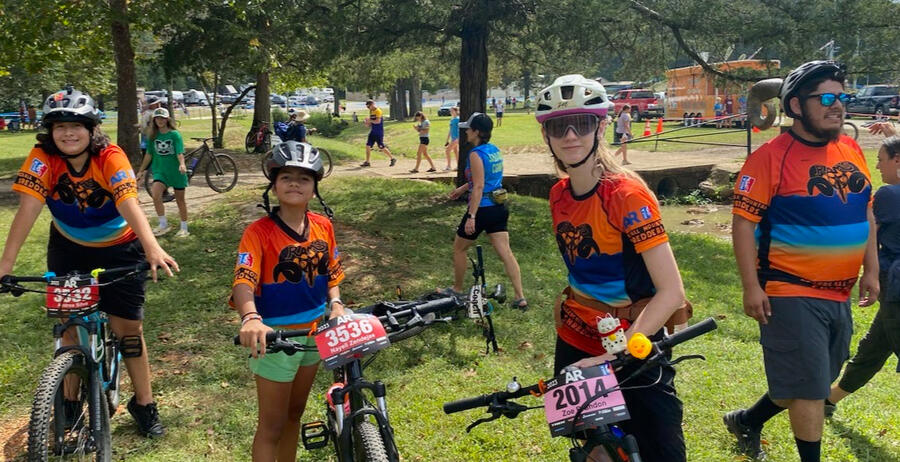 Three student riders on bikes and a coach